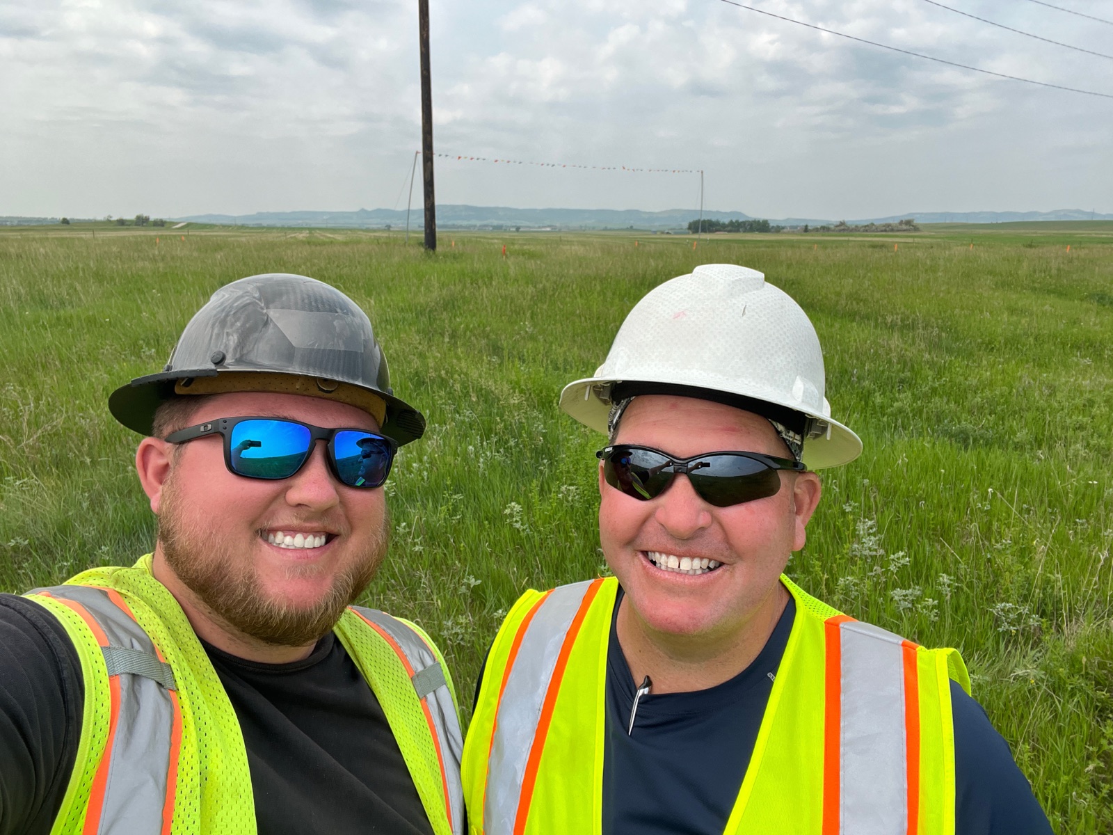 Caleb Jones and his father in hard hats and high-visibility vests on a pipeline right-of-way